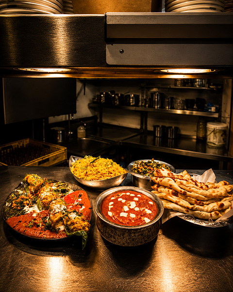The Bhajipala kitchen pass with fresh curries, biryani and naan under warm lights